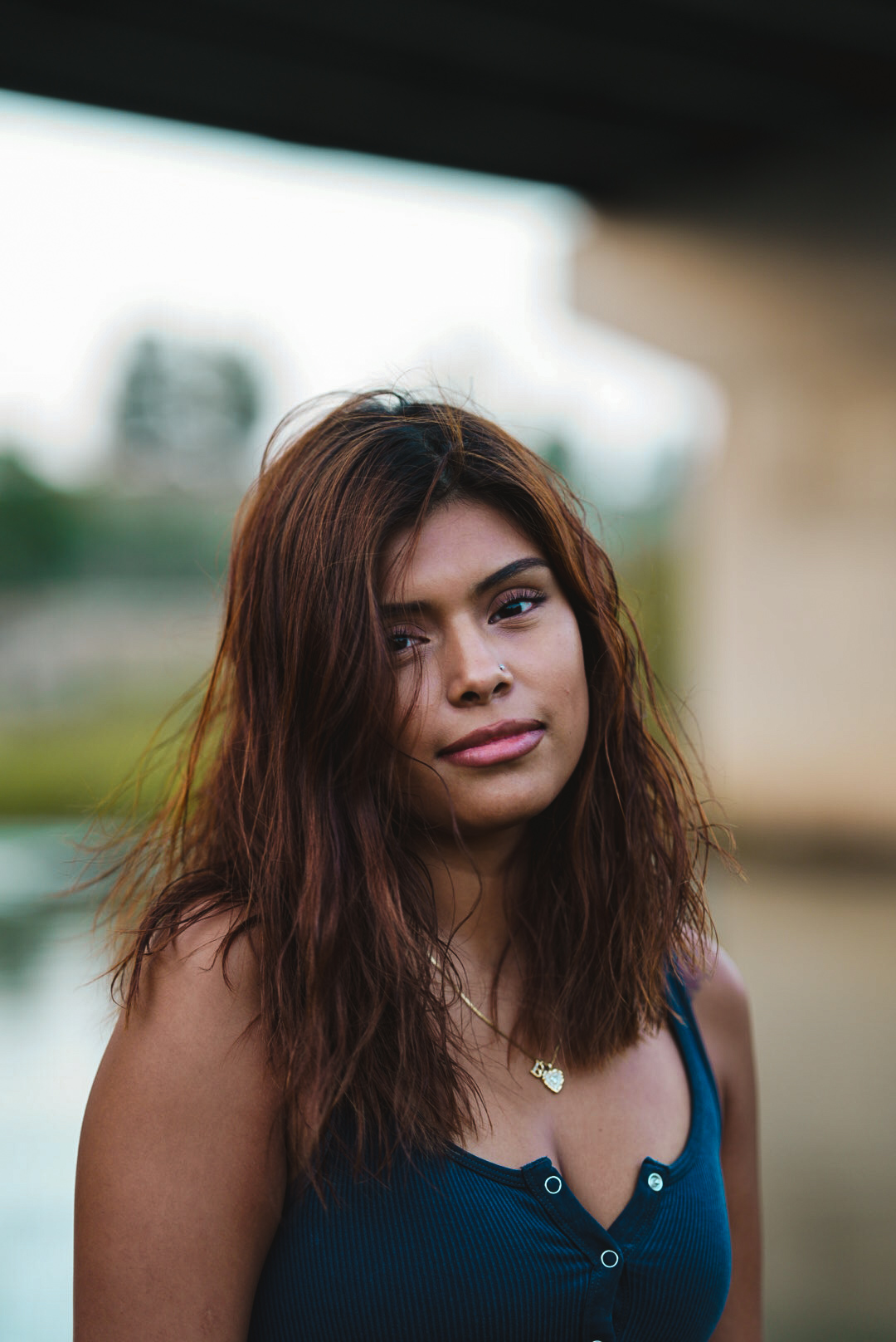 Golden hour portrait of a woman beside a river under a bridge