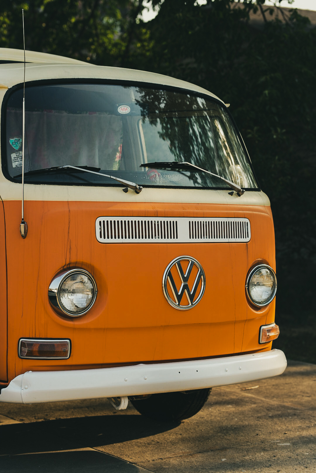 Front of a classic orange and cream Volkswagen bus at golden hour
