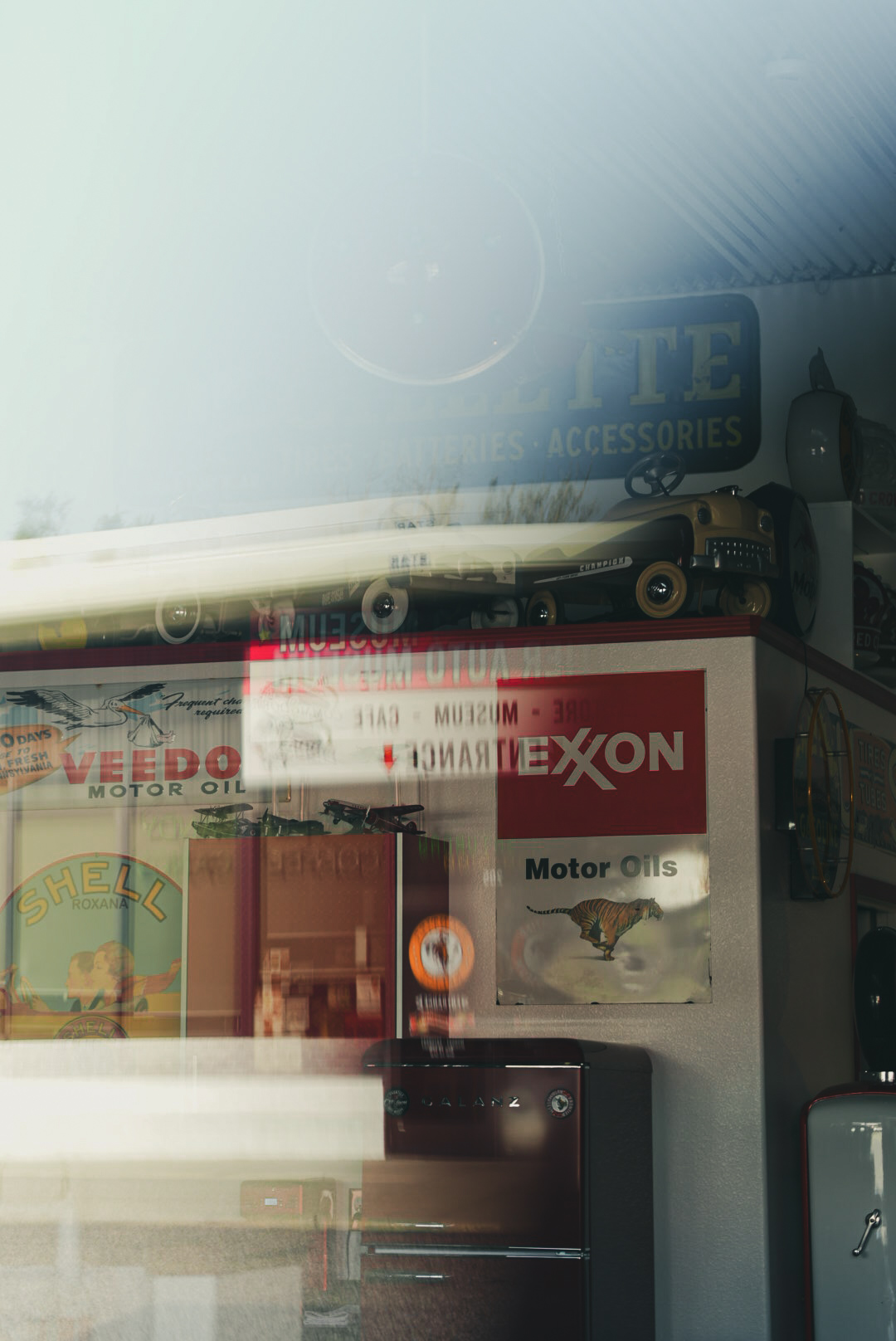 Vintage Exxon and Shell motor oil signage reflected in an auto museum window