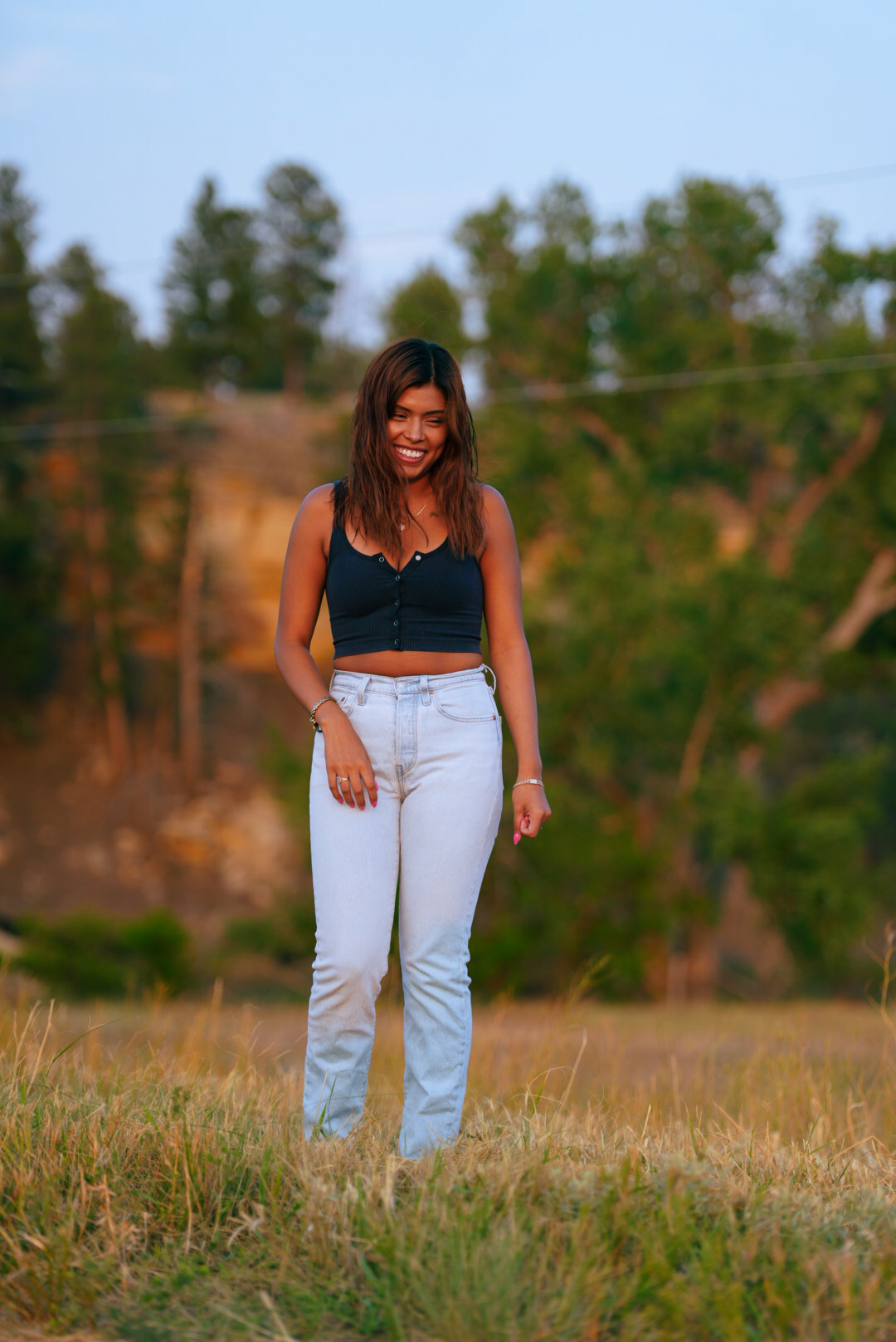 Woman laughing while standing in tall grass with sandstone bluffs behind her