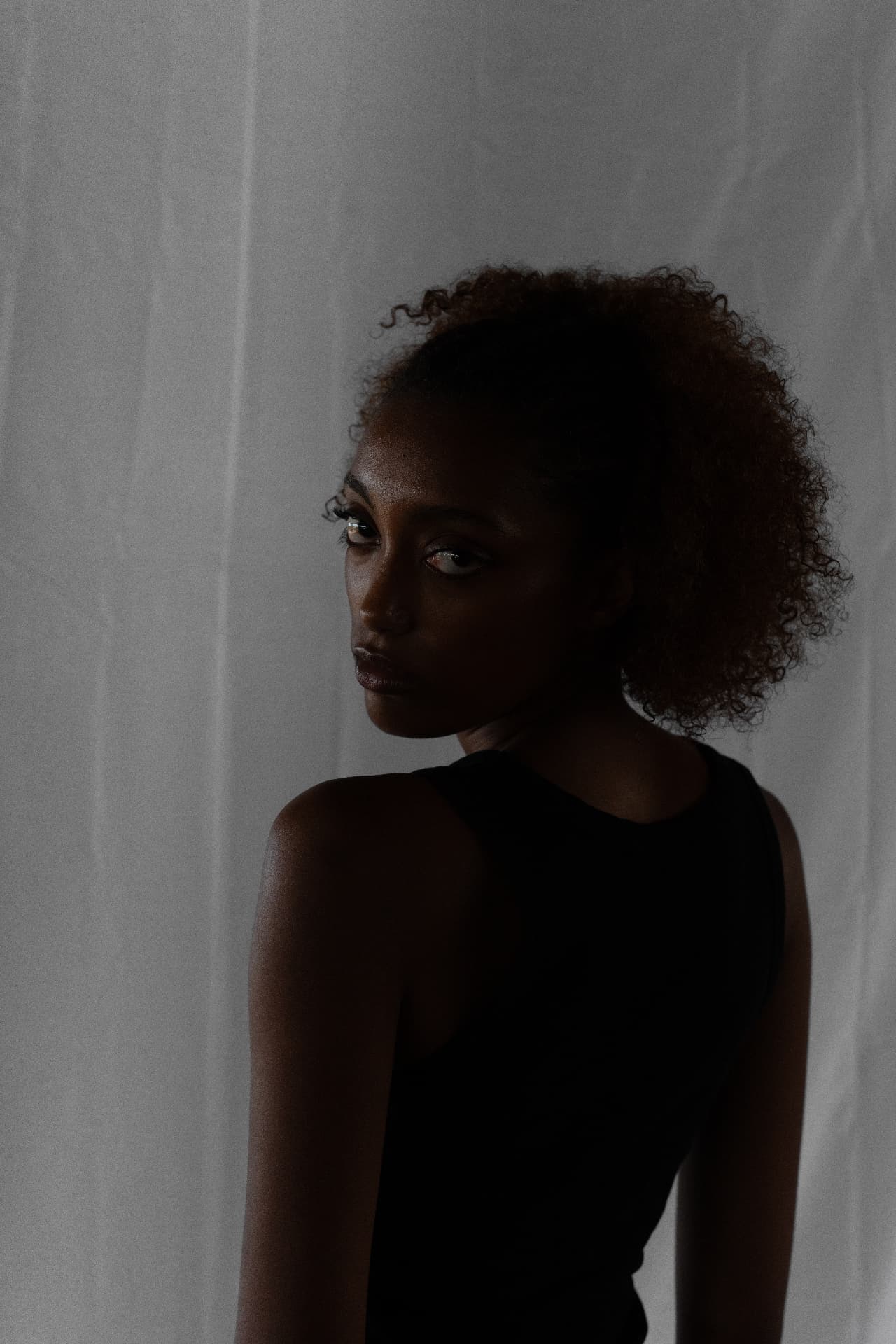Moody low-key studio portrait of a woman turning toward the camera