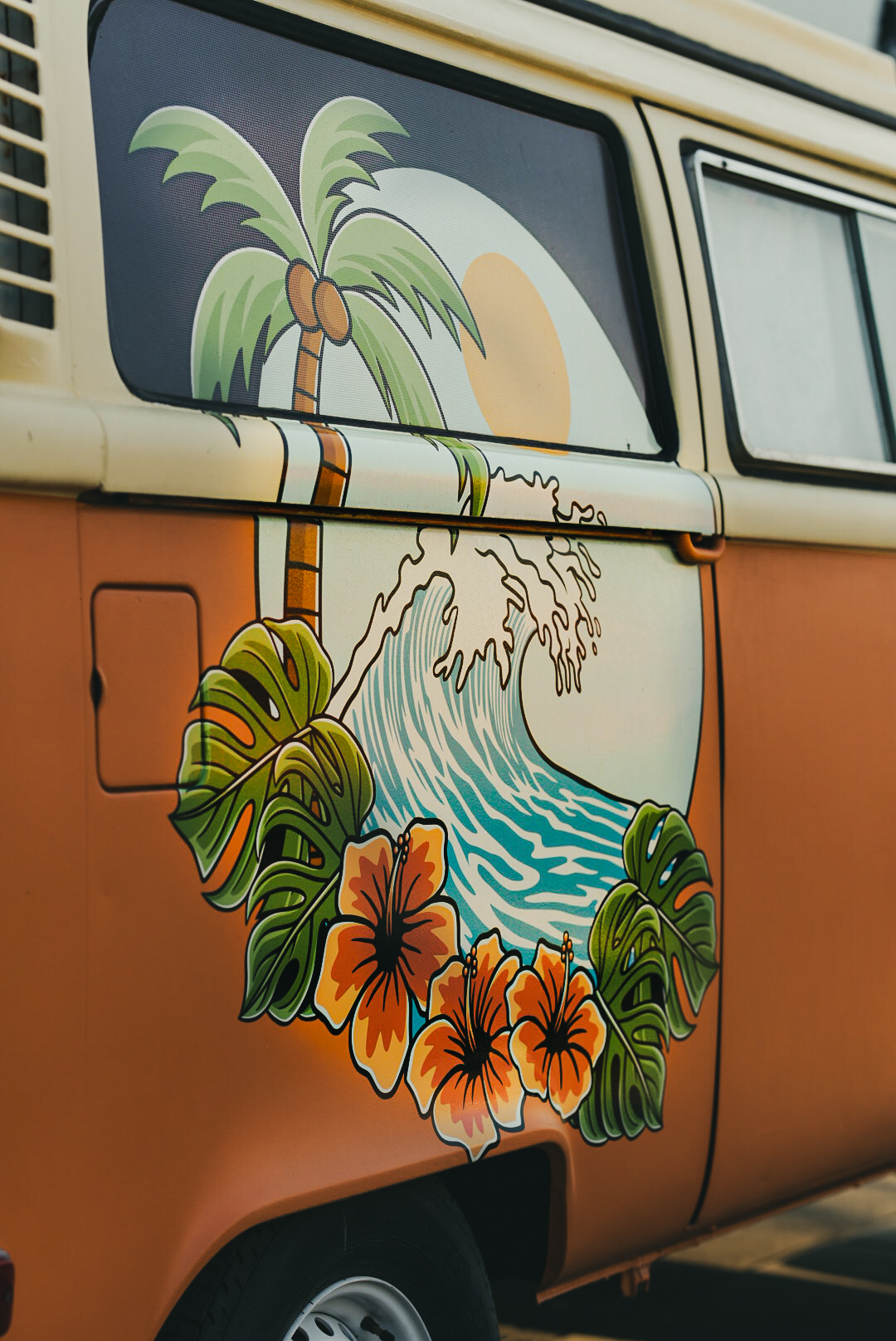 Hand-painted wave and hibiscus mural on the side of an orange VW bus