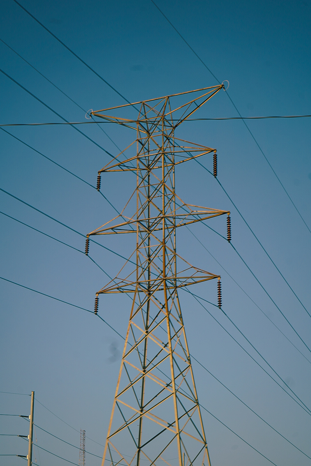 Steel transmission tower and power lines against a clear blue sky
