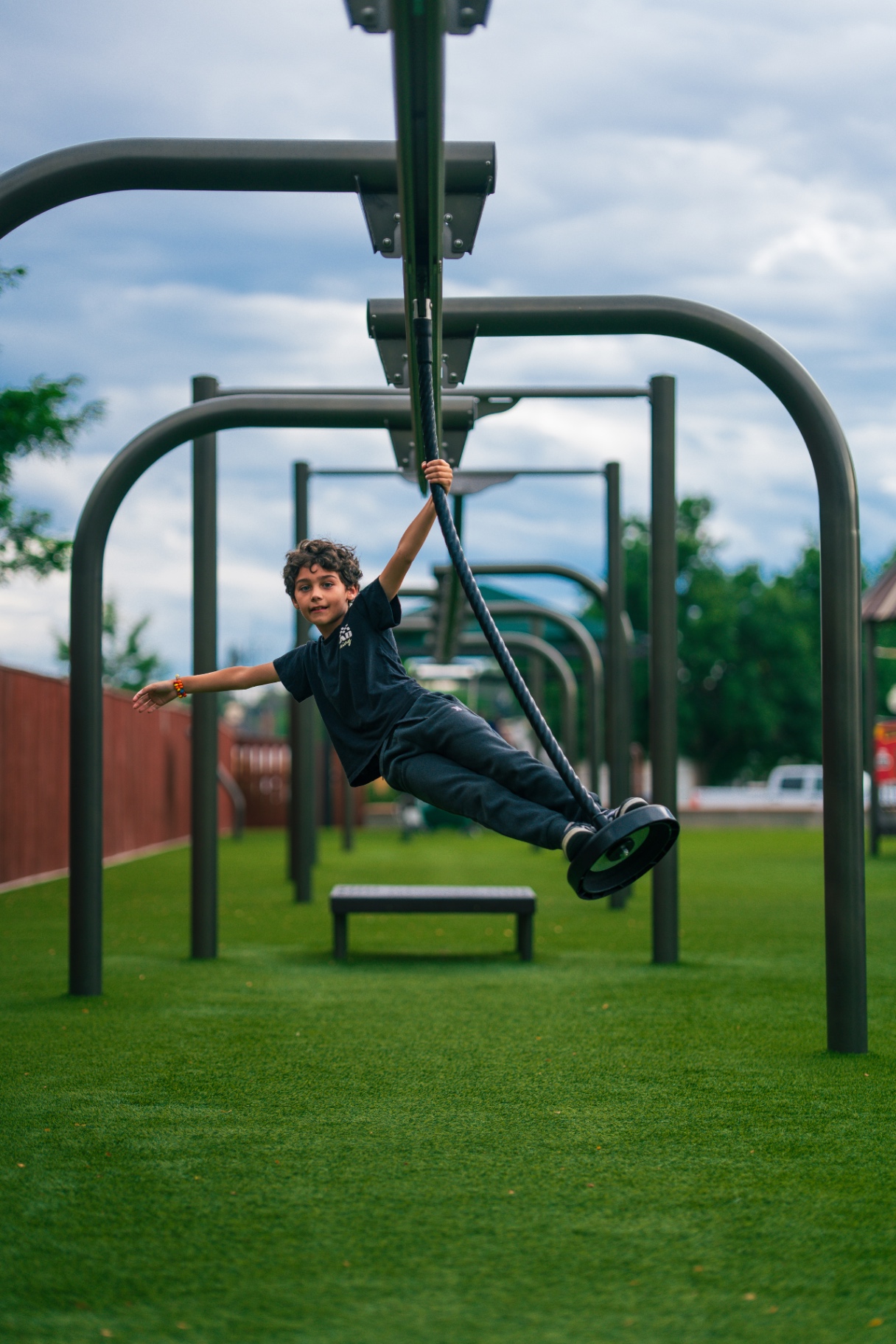 Boy swinging from a playground zipline with one arm outstretched