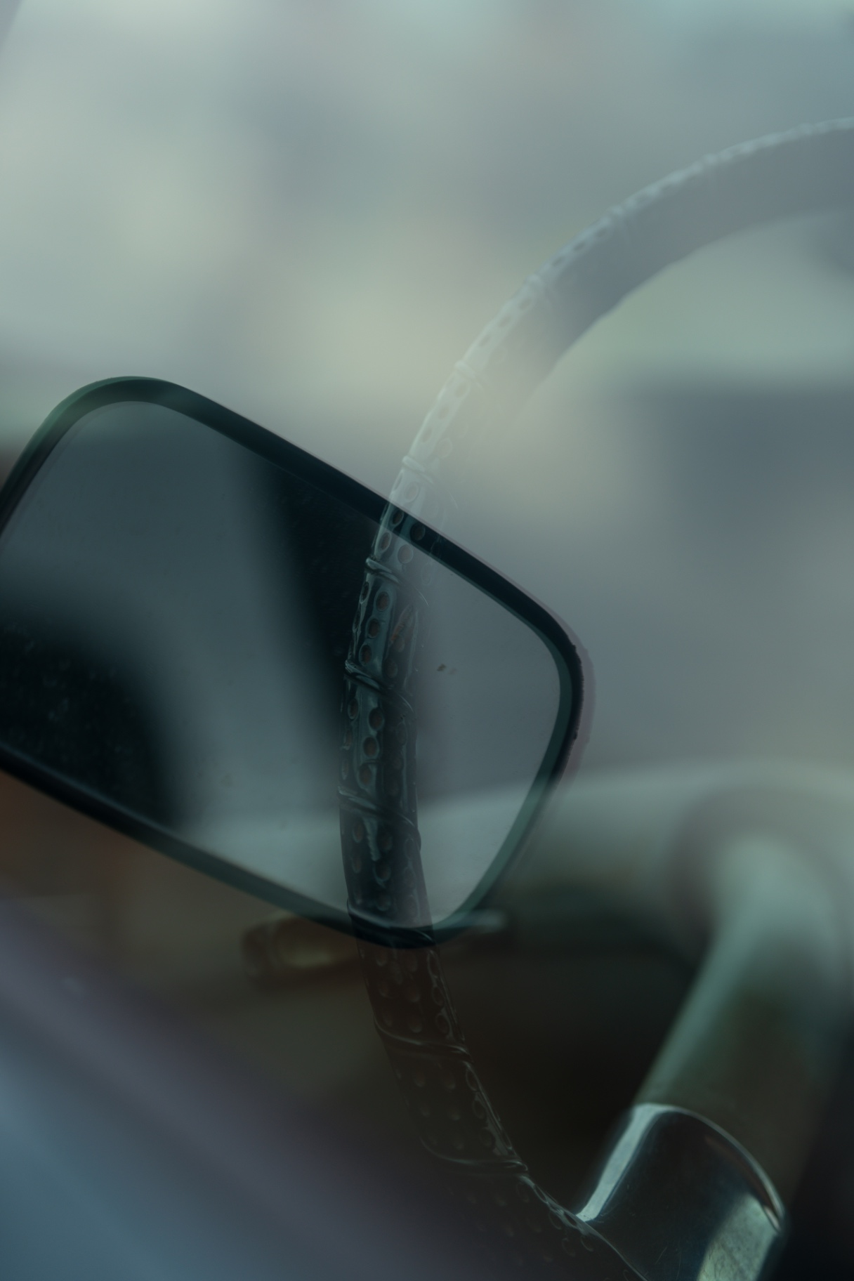 Abstract reflection of a steering wheel and mirror through car glass