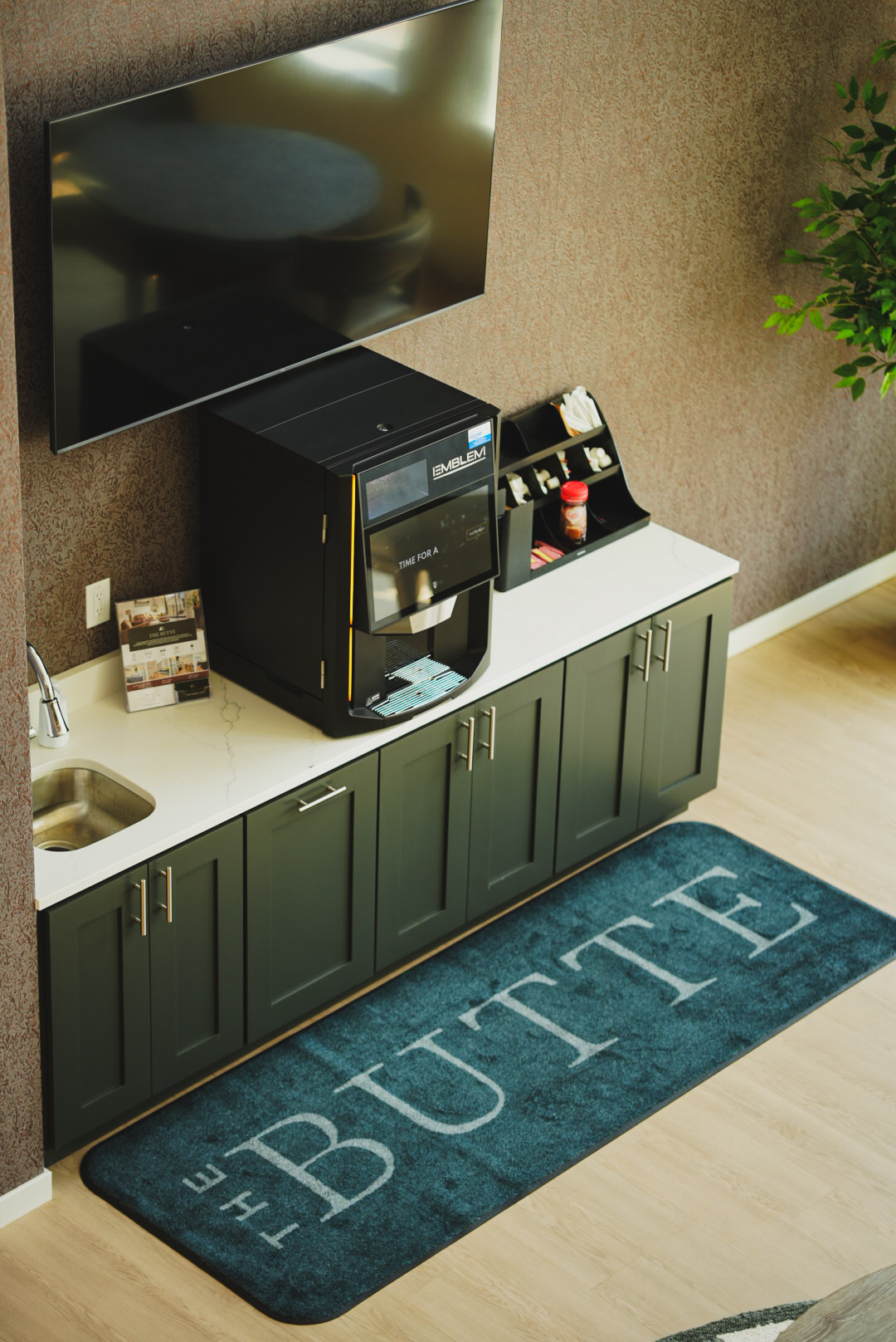 Green cabinet coffee bar with espresso machine and branded floor mat