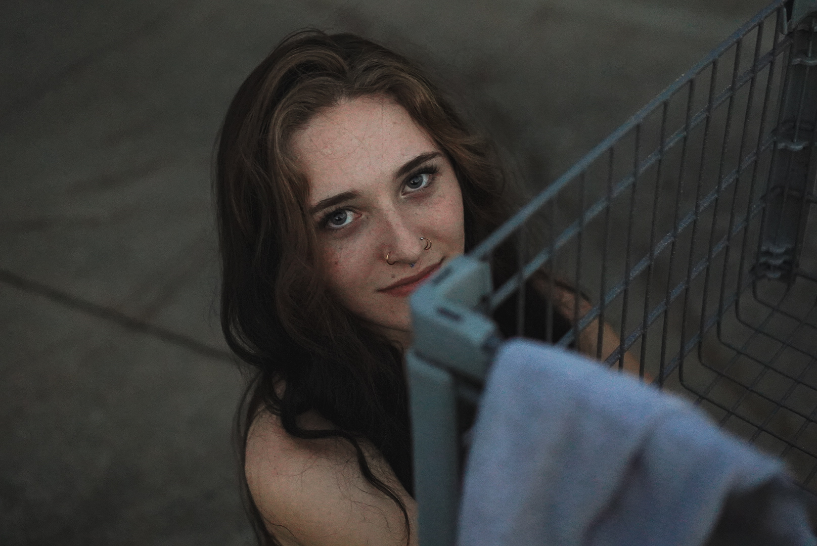 Moody overhead portrait of a woman beside a shopping cart at dusk