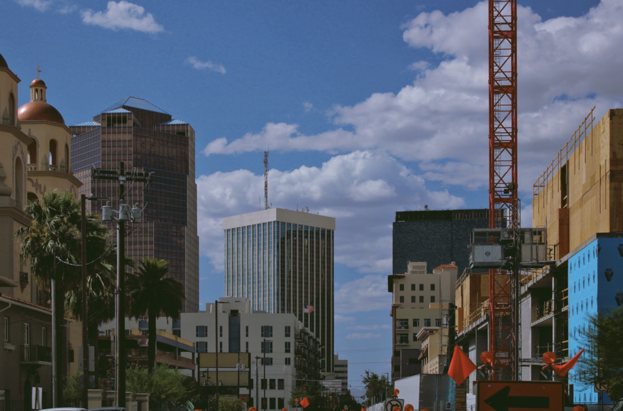 Downtown skyline with a red construction crane under bright clouds