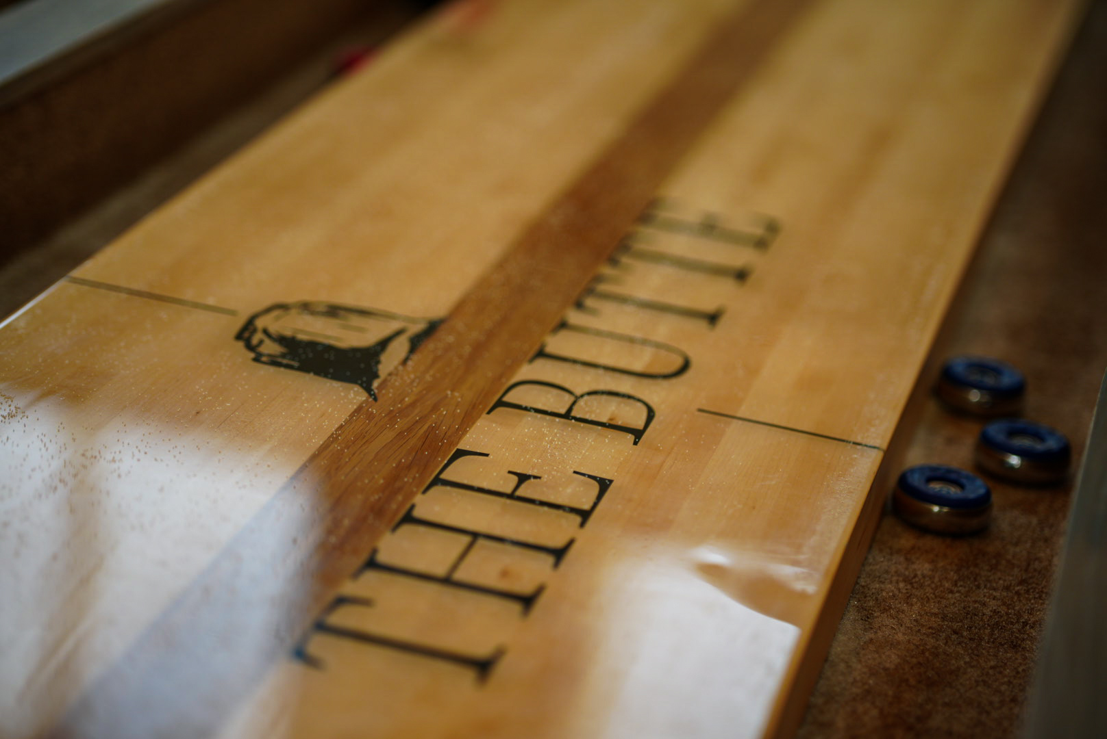 Close-up of a shuffleboard table surface engraved with The Butte logo