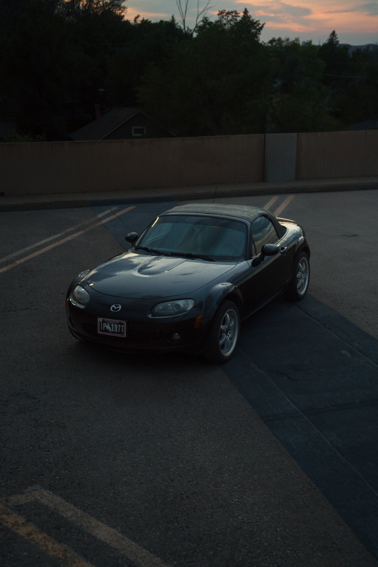 Black Mazda MX-5 roadster parked on a lot at sunset