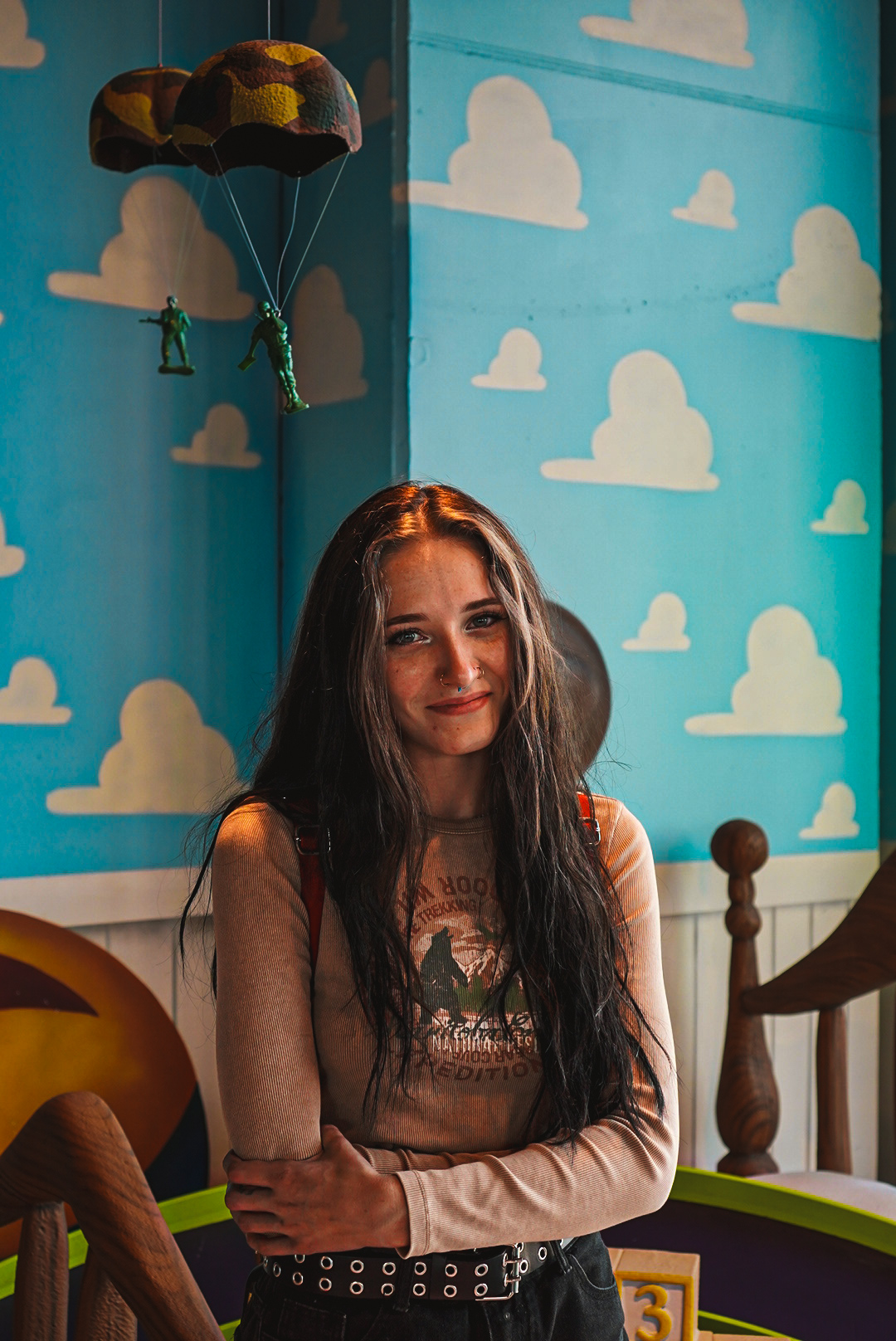 Portrait of a woman in a toy-themed room with a painted blue cloud wall