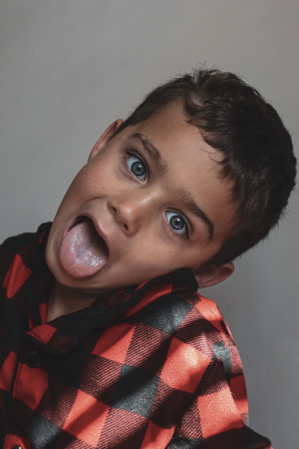Boy tilting his head and sticking out his tongue in a studio portrait
