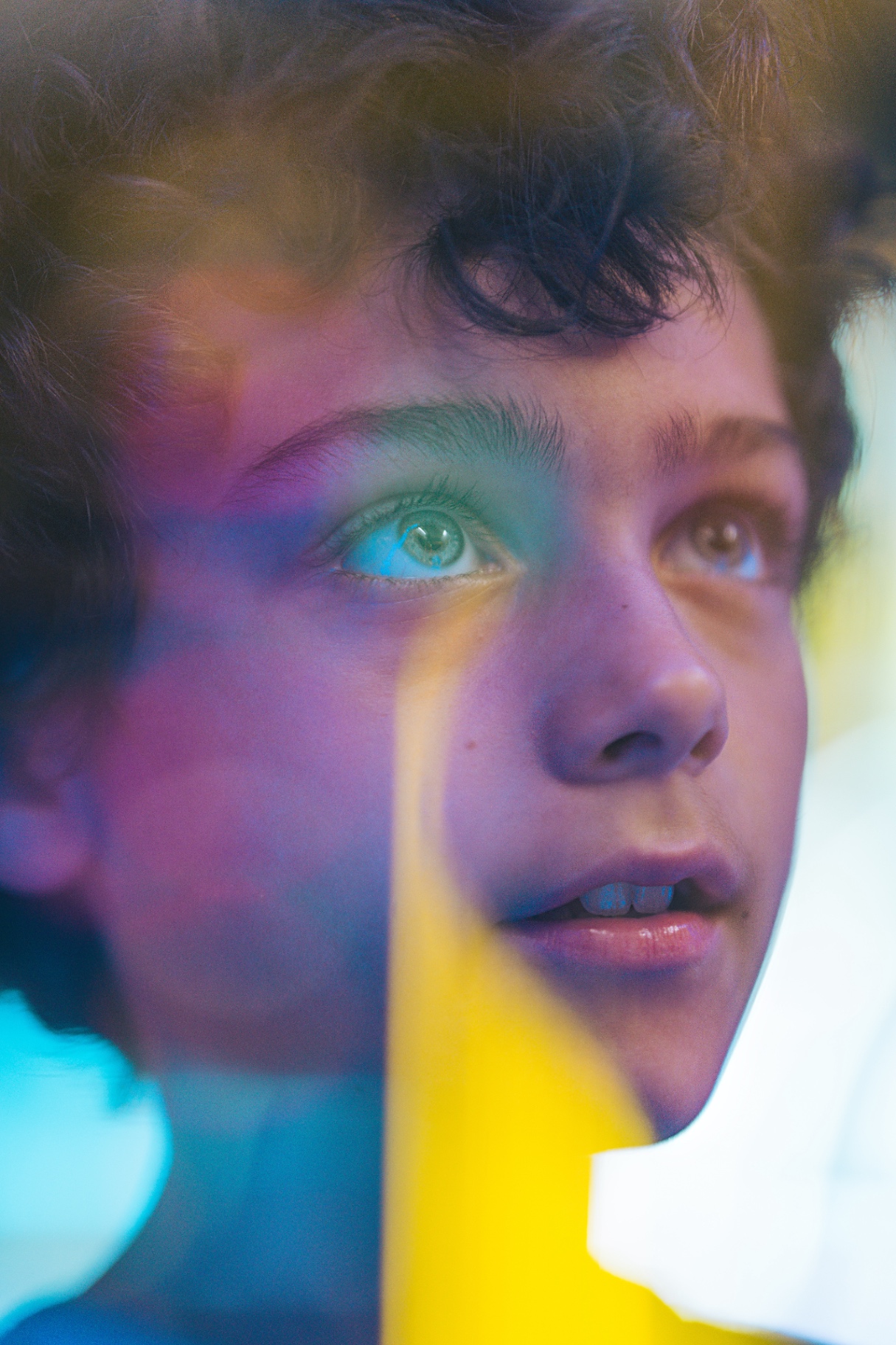 Close-up of a boy's face washed in colorful prismatic light