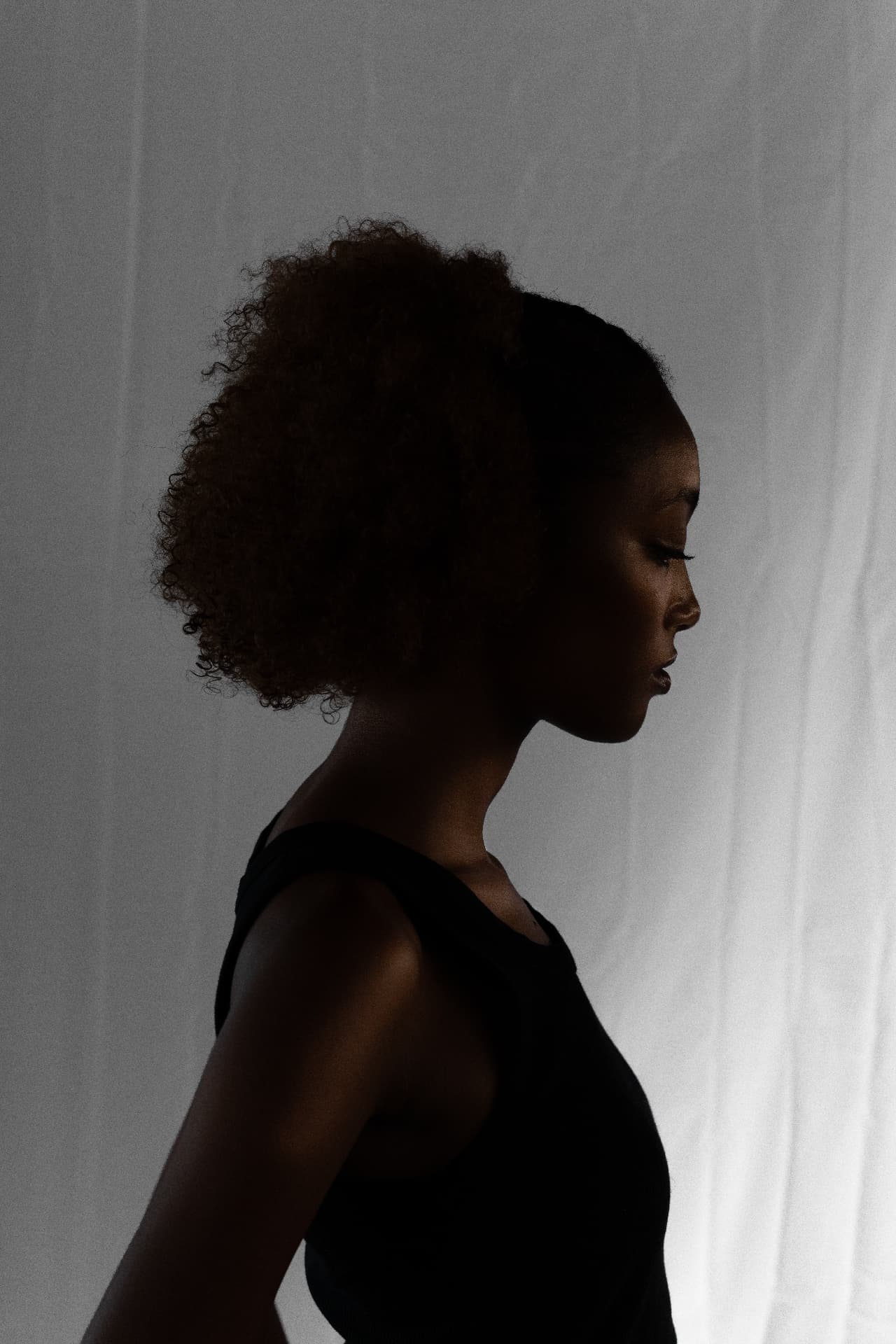 Low-key side profile portrait fading into shadow