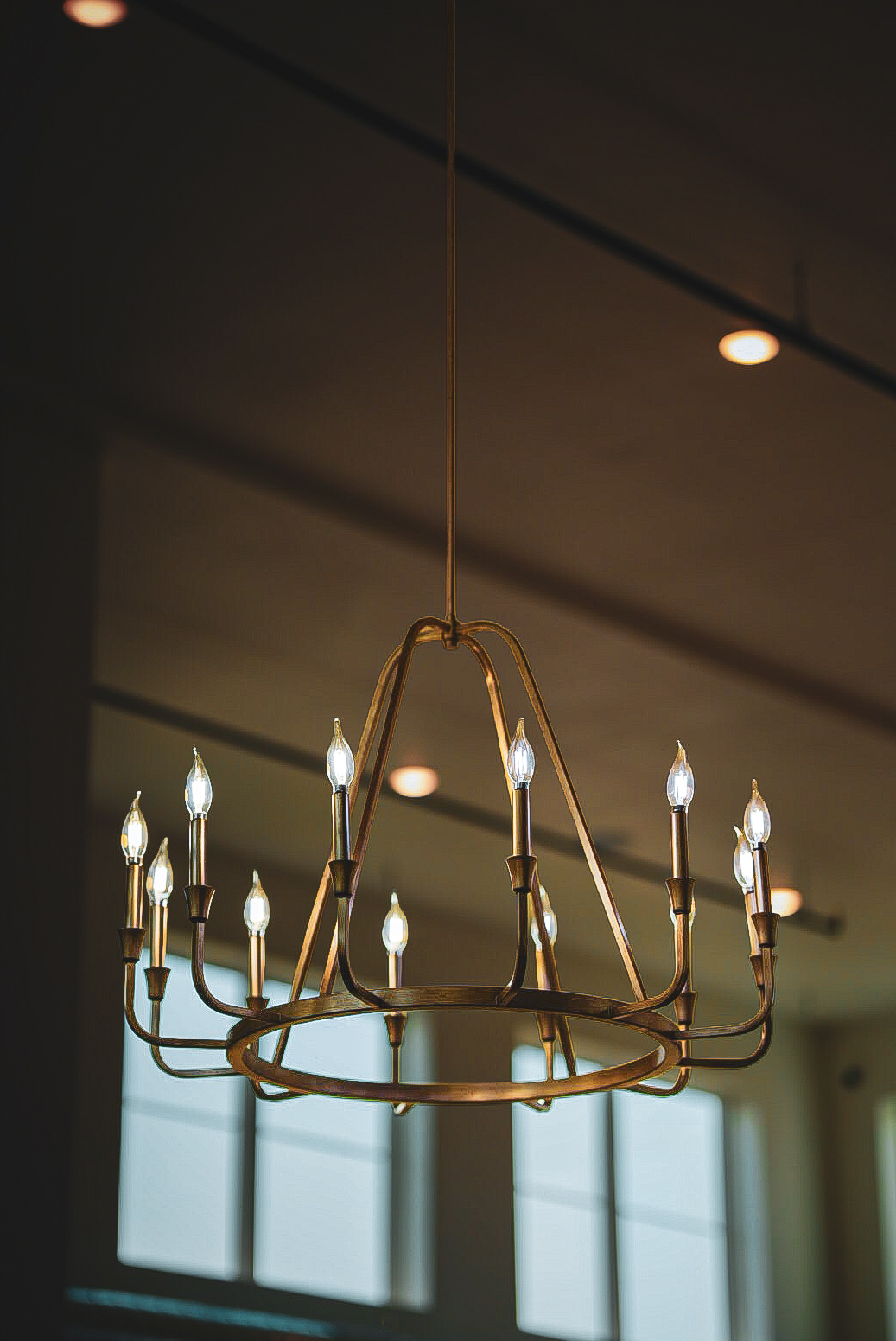 Antique brass ring chandelier with candle bulbs against a dark ceiling