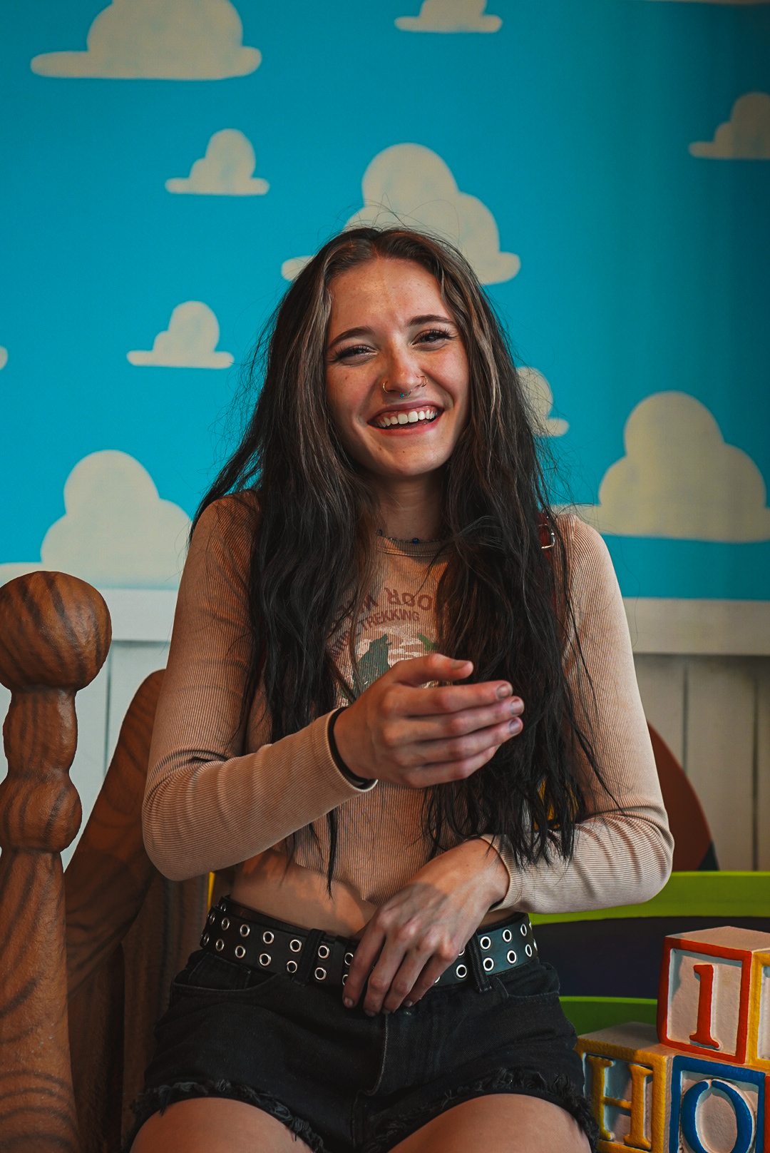 Woman laughing while seated in front of a painted cloud wall