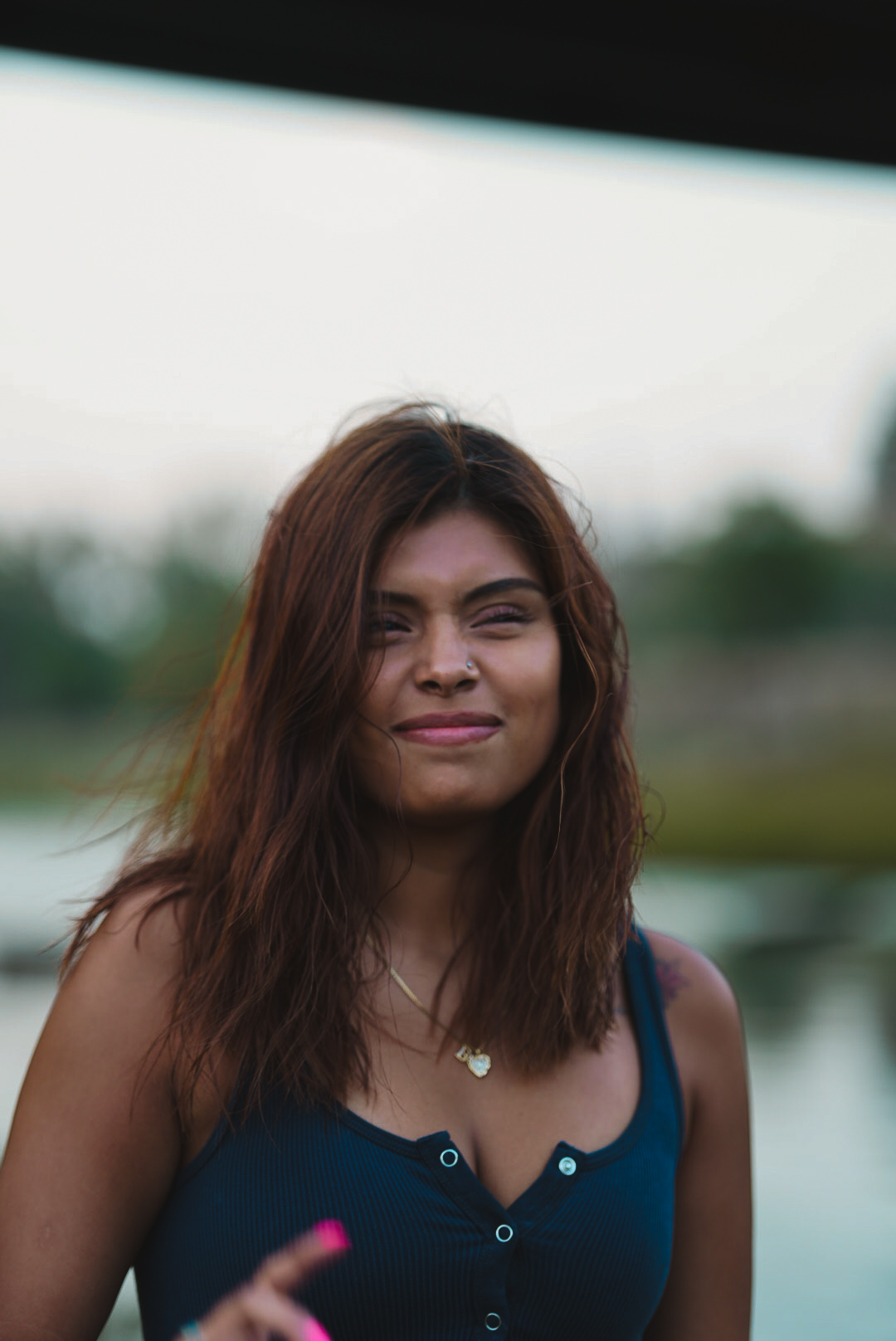 Woman smiling and squinting in soft evening light by the water