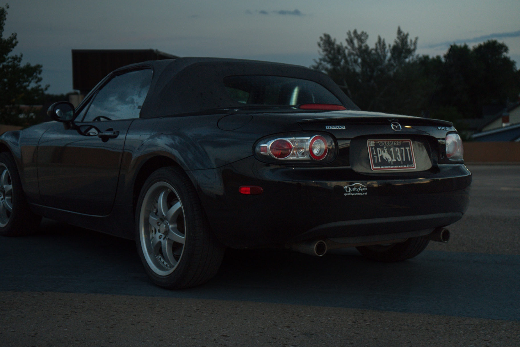 Rear quarter of a black Mazda MX-5 in blue hour light